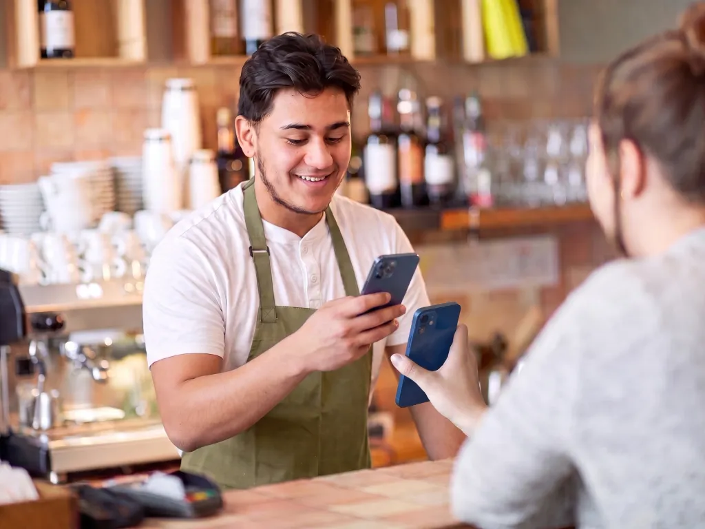 A barista scans the loyalty card on a customer's phone to add a stamp.